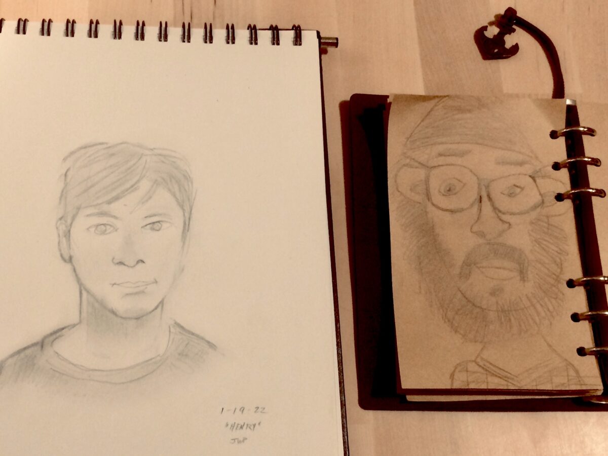 Two art notebooks with one containing sketch of son on left and father on right