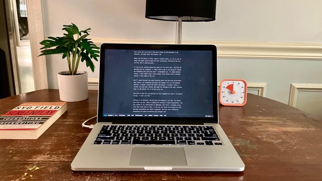 Writing set-up which includes laptop, timer, and Syd Field's book Screenplay: The Foundations of Screenwriting