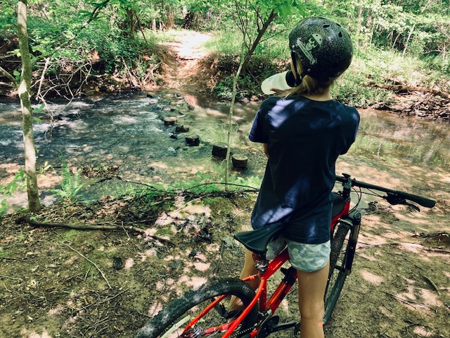 Cyclist drinks from water bottle at creek crossing