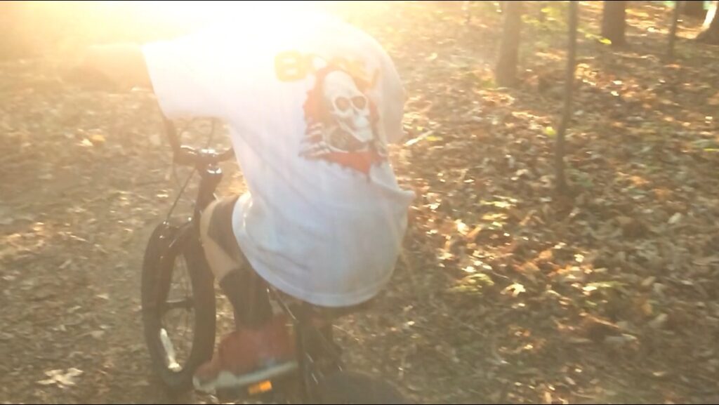 boy rights bike through the forest